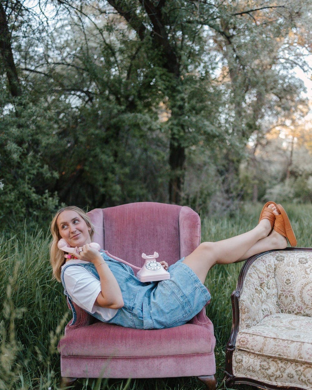 Brooklyn in a pink velvet chair, on a rotary phone
