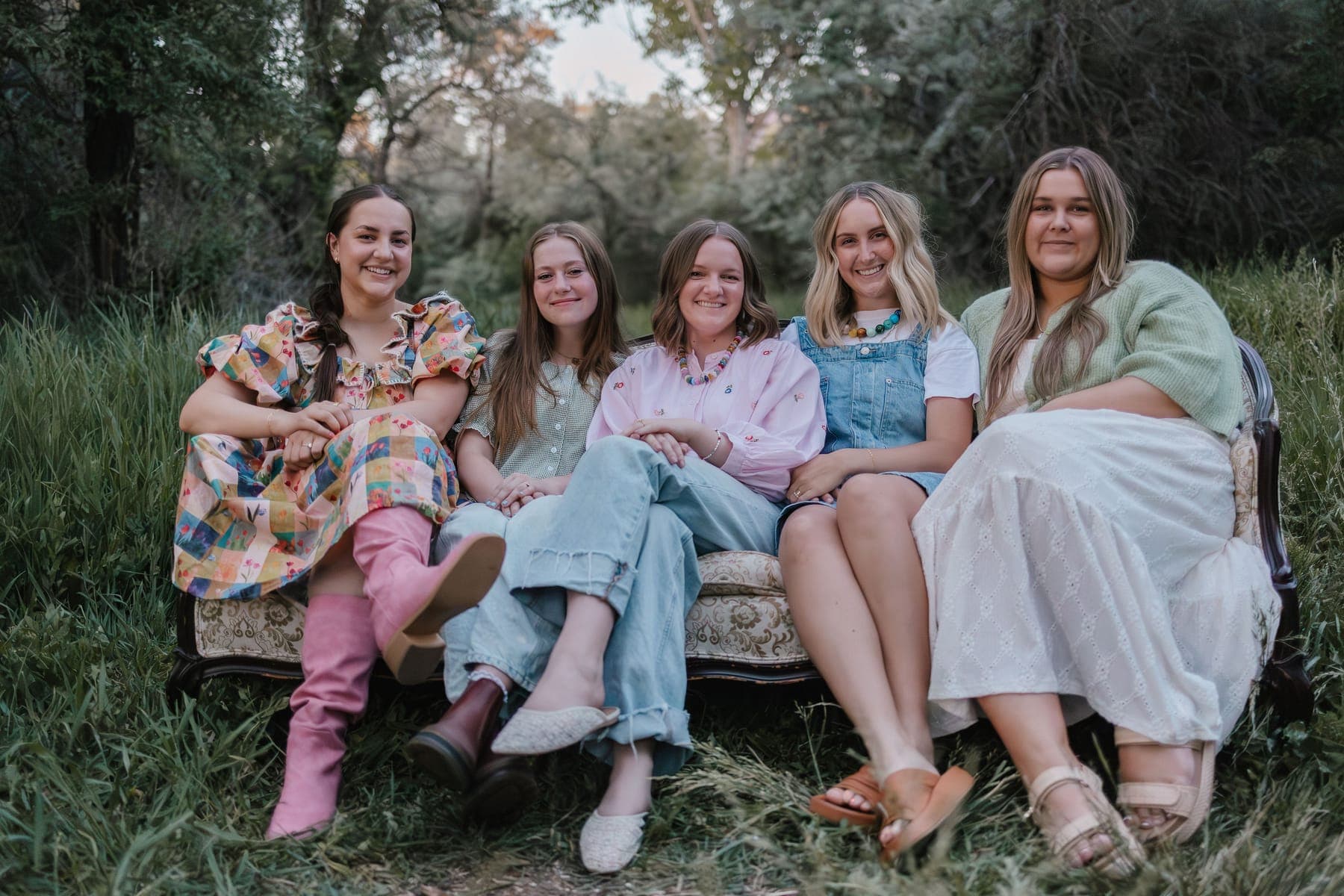The Embrace Media team sitting together on a vintage floral couch in a field